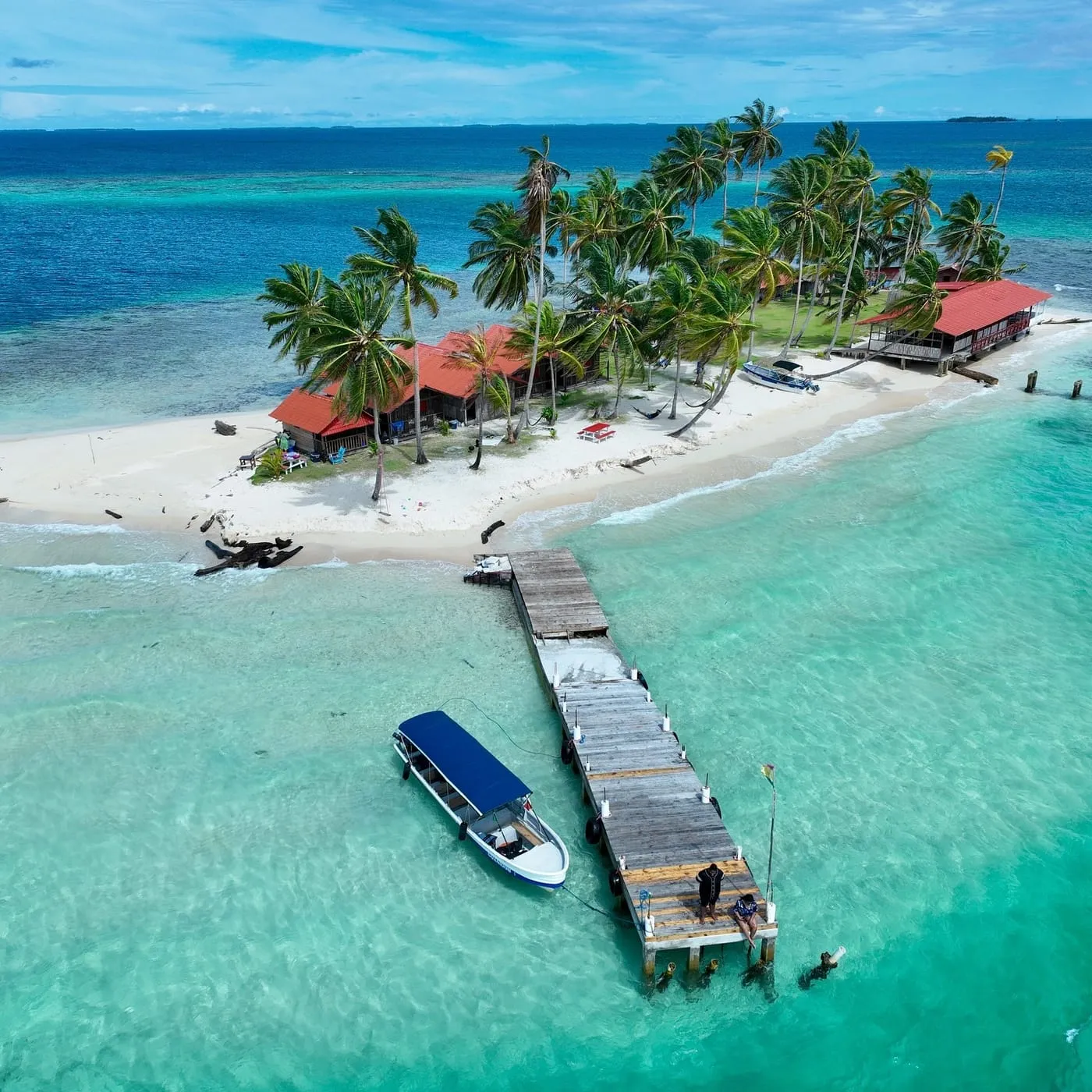 Aerial view of an island with a long wooden dock and a boat moored alongside in Guna Yala
