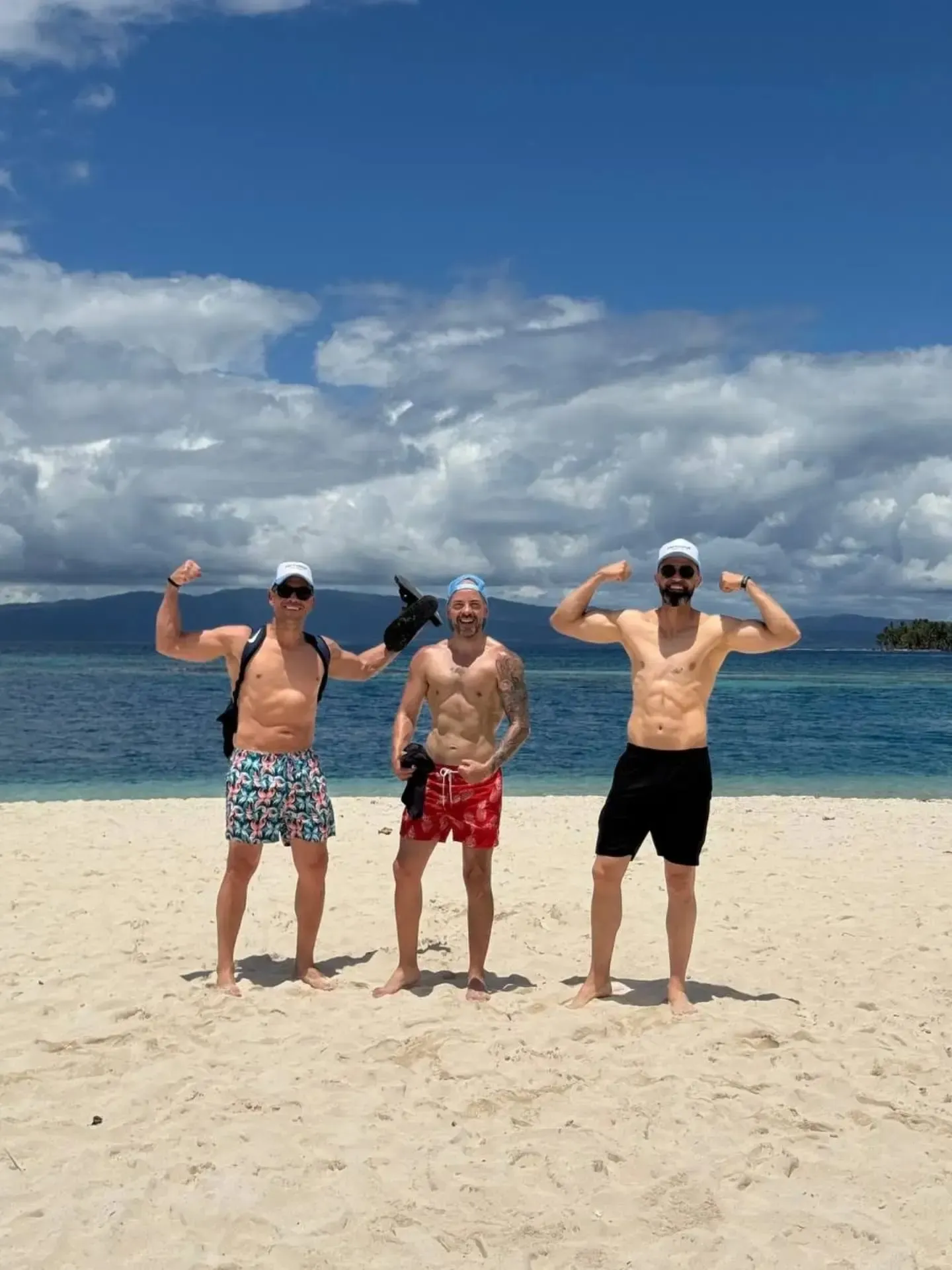 Tres amigos posando y riendo en la playa de arena blanca de una isla de San Blas
