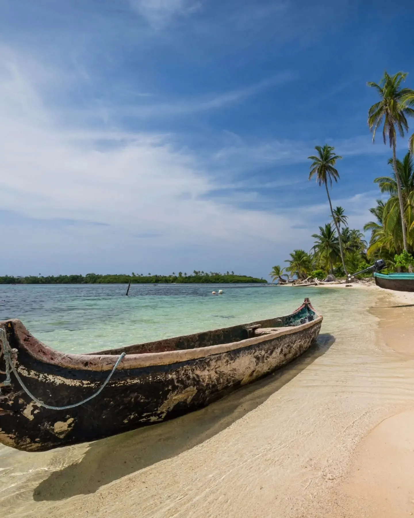 A traditional wooden cayuco pulled up on the sand of a palm-lined island in Guna Yala