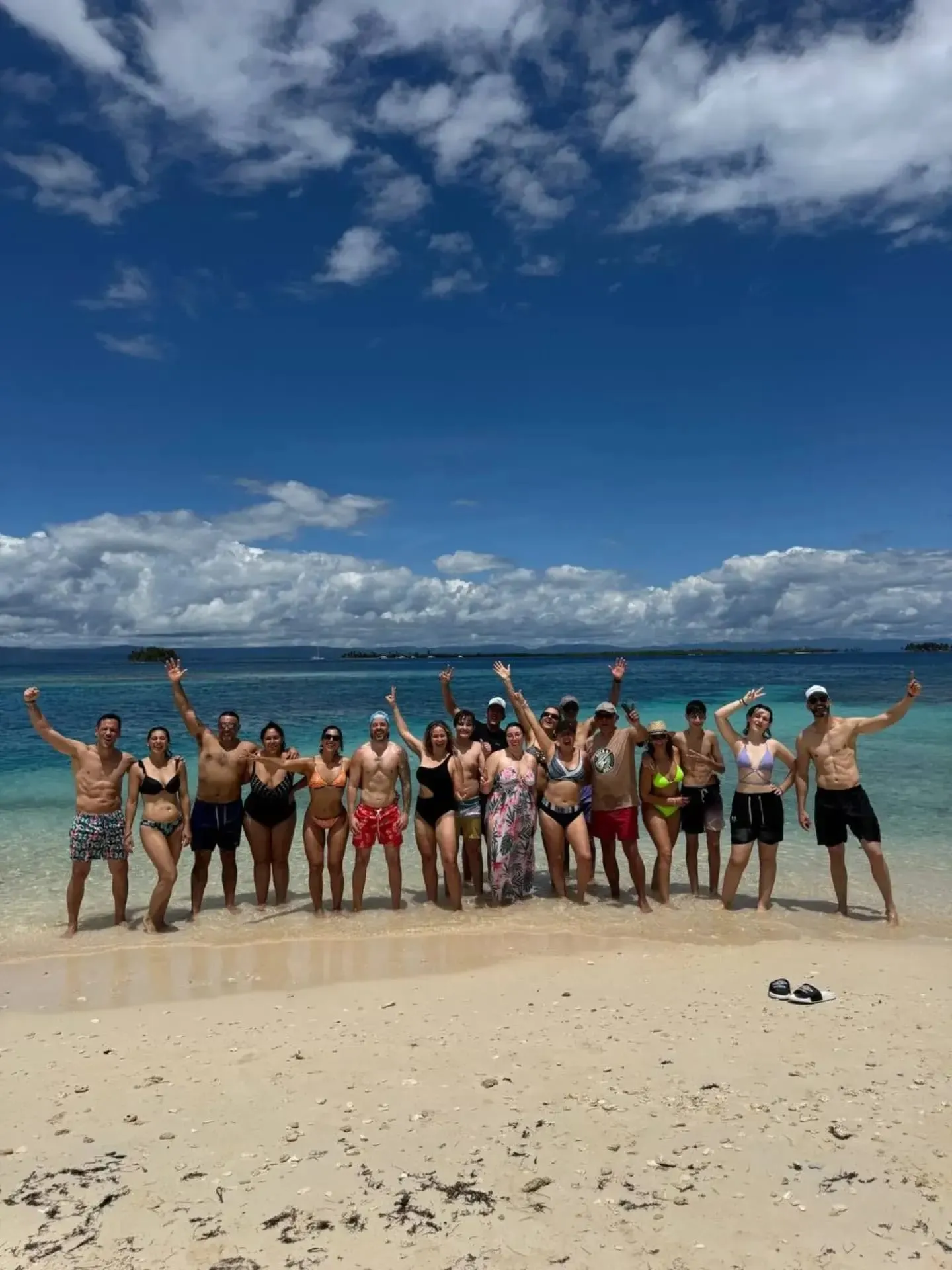 A large group of travelers posing together on a white-sand beach in Guna Yala