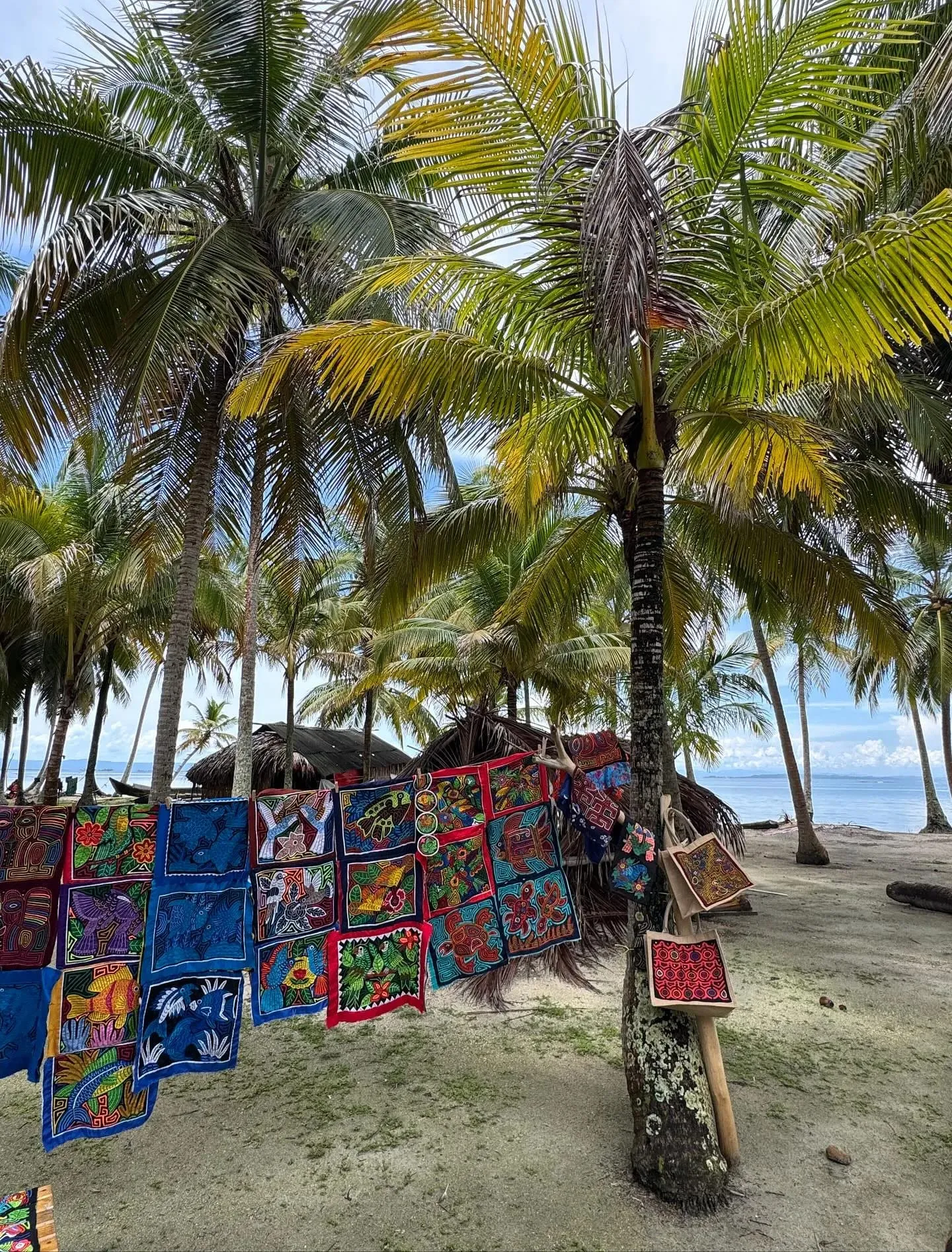 Brightly colored molas hanging between palm trees on a Guna Yala island