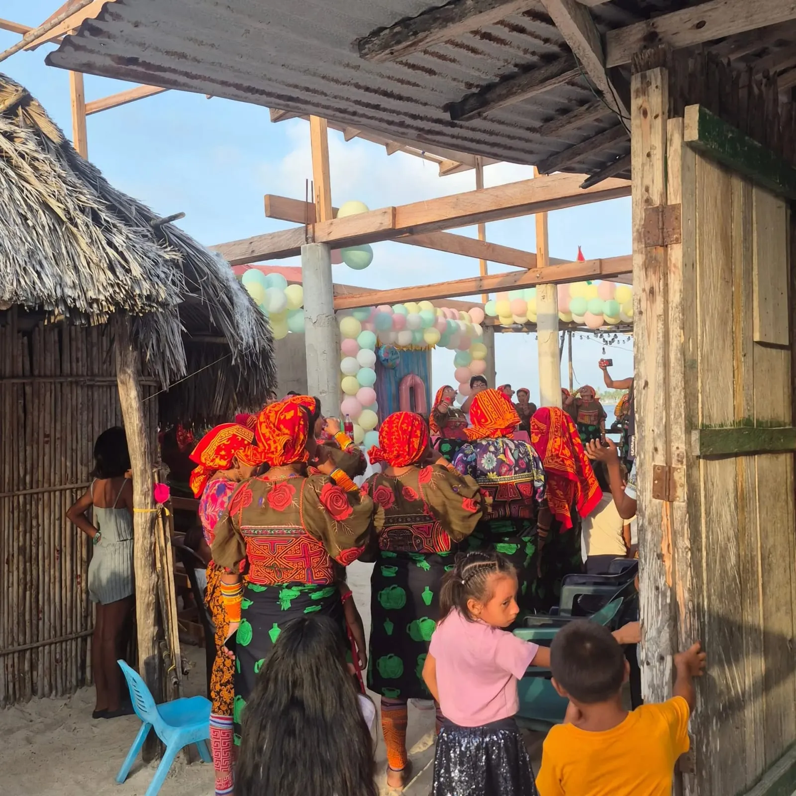 Mujeres Guna con blusas de mola tradicionales reunidas en una celebración comunitaria bajo un techo de paja