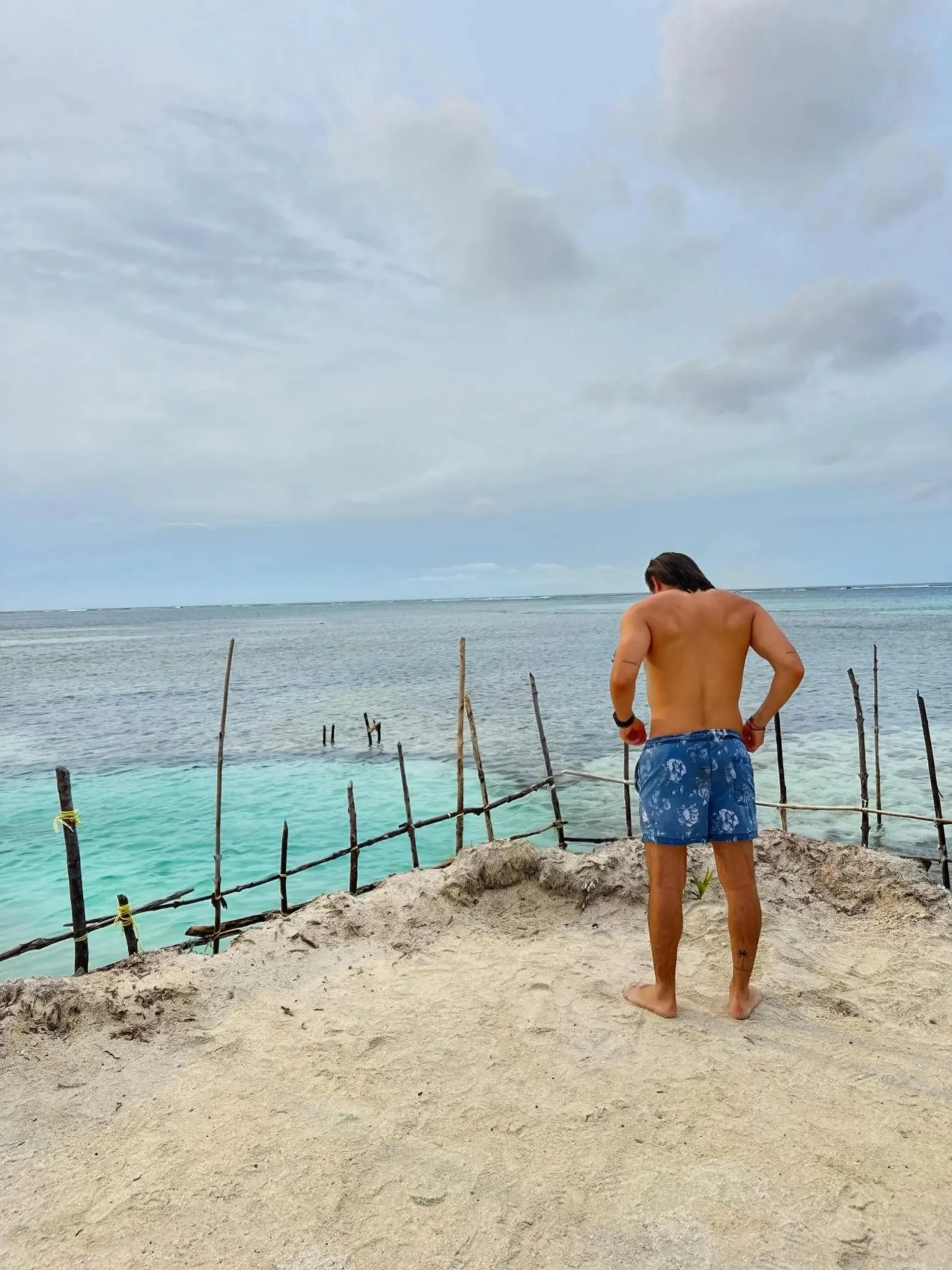 A traveler alone on a quiet beach in Guna Yala, looking out at the shallow water
