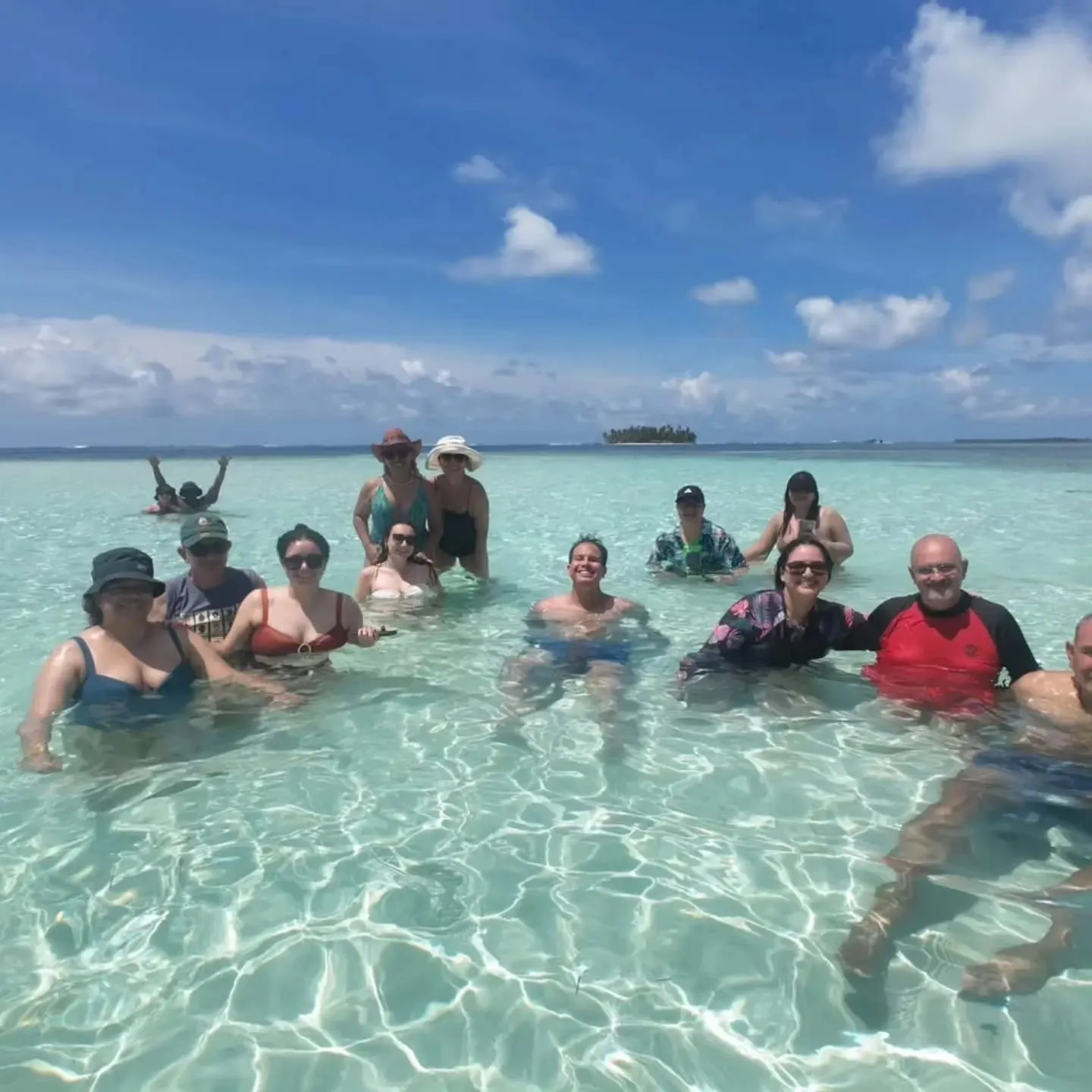 A small group of travelers standing waist-deep in the clear water of the Piscina Natural in Guna Yala